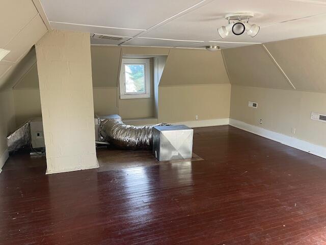 bonus room with baseboards, vaulted ceiling, and wood finished floors