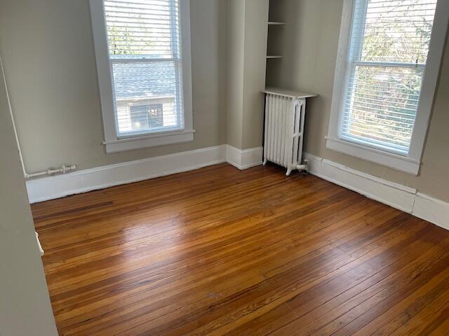 spare room featuring radiator, baseboards, and hardwood / wood-style floors