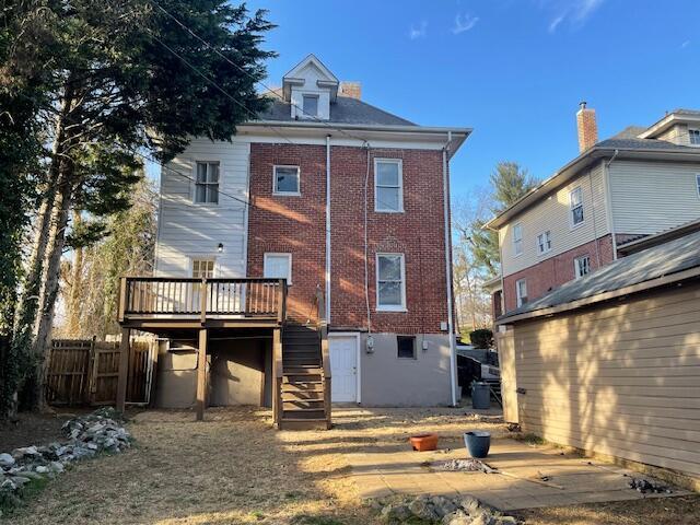 back of property featuring a wooden deck, fence, stairway, and brick siding