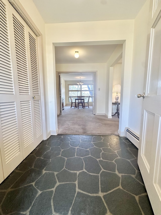 hallway with stone finish floor, baseboards, dark carpet, and baseboard heating