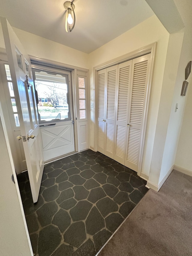 foyer featuring dark carpet and baseboards