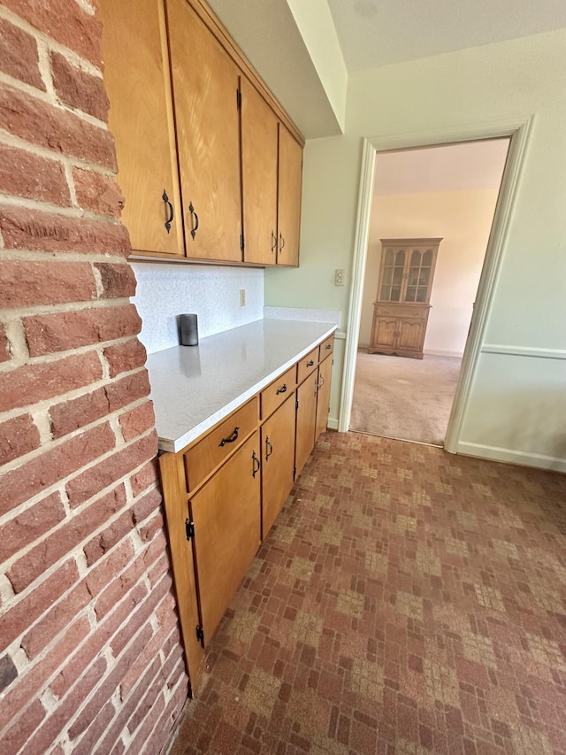 kitchen with brick floor, light countertops, and baseboards