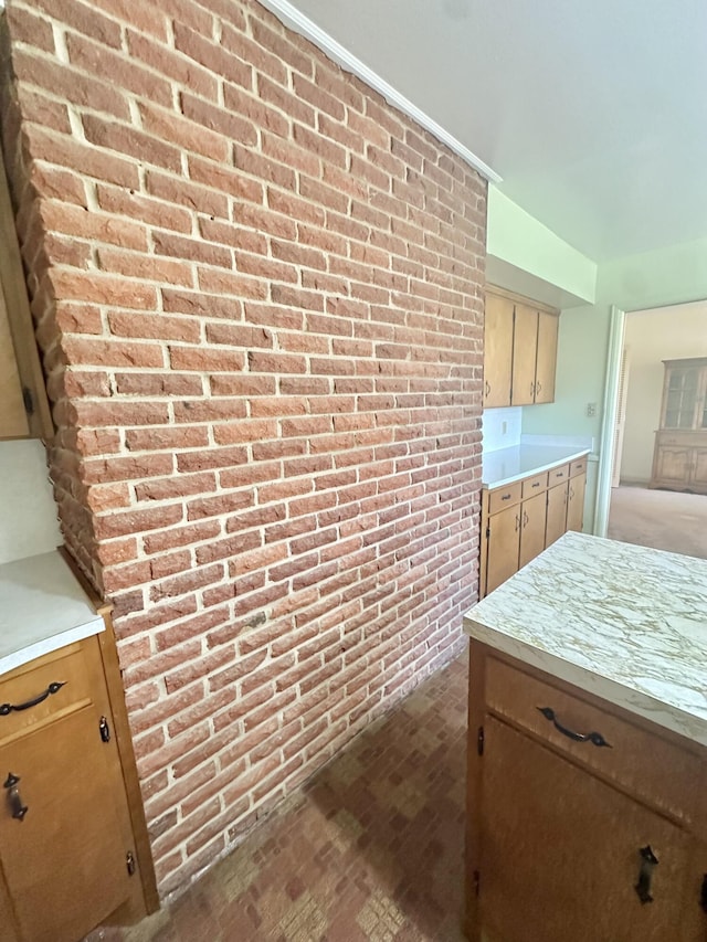 kitchen featuring brick wall and light countertops