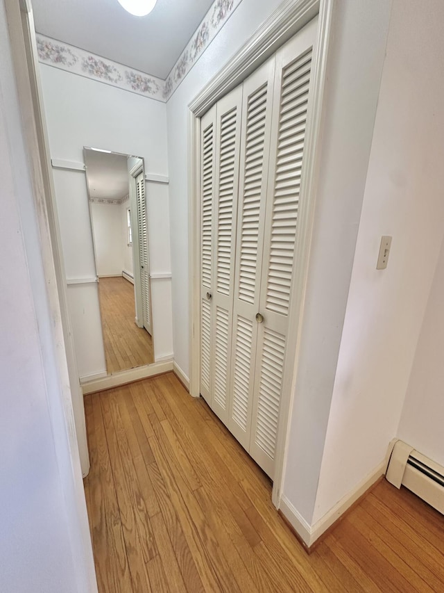 hall featuring light wood-type flooring, baseboards, and baseboard heating