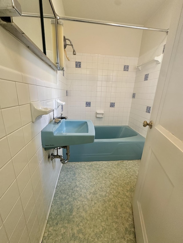 full bath featuring shower / bath combination, a sink, and tile walls