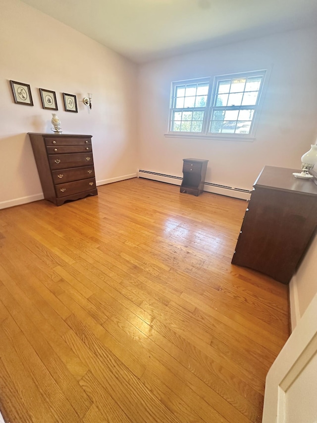 bedroom featuring light wood-style flooring, baseboards, and baseboard heating