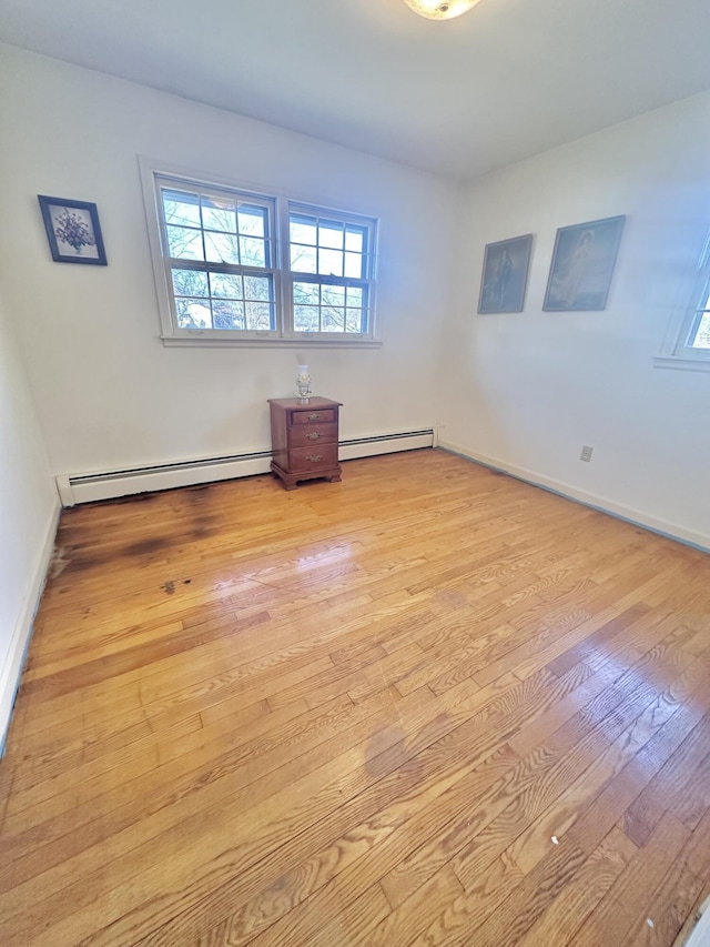 empty room featuring light wood-style flooring, baseboards, and baseboard heating