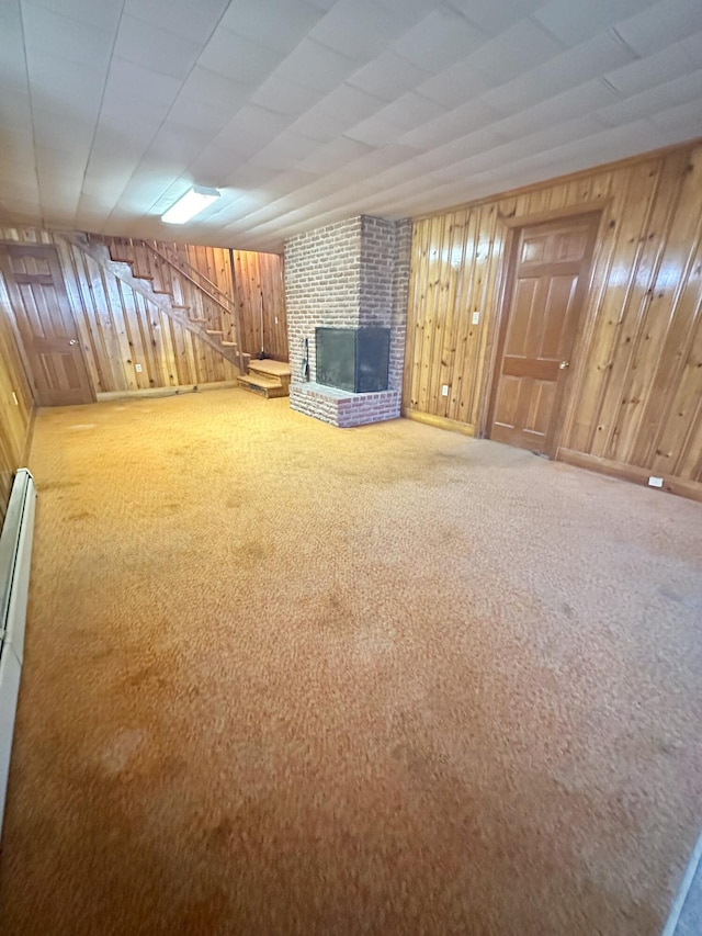 unfurnished living room featuring carpet, a fireplace, stairs, and wooden walls