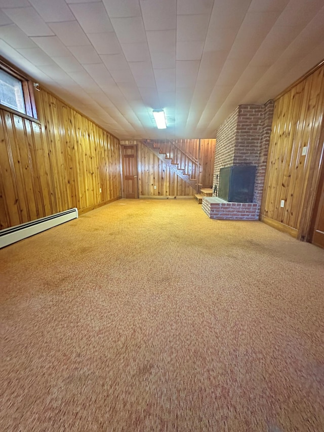 unfurnished room featuring baseboard heating, a brick fireplace, carpet flooring, and wooden walls