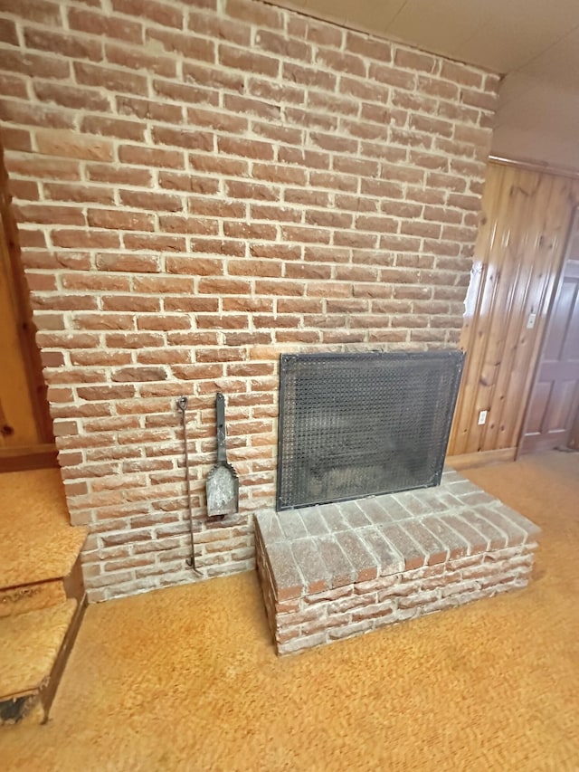 room details featuring wood walls, a fireplace, and carpet flooring