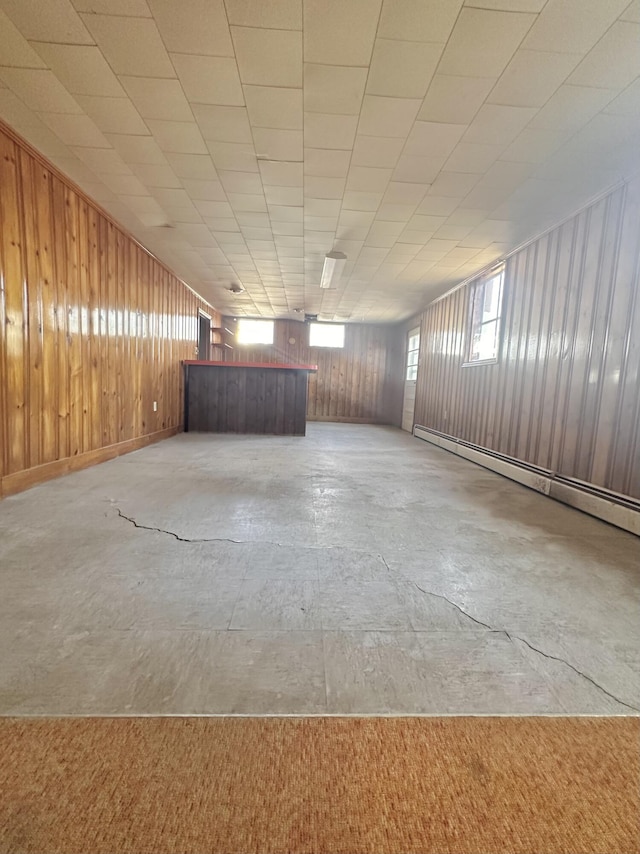 spare room with concrete floors, wooden walls, and baseboard heating