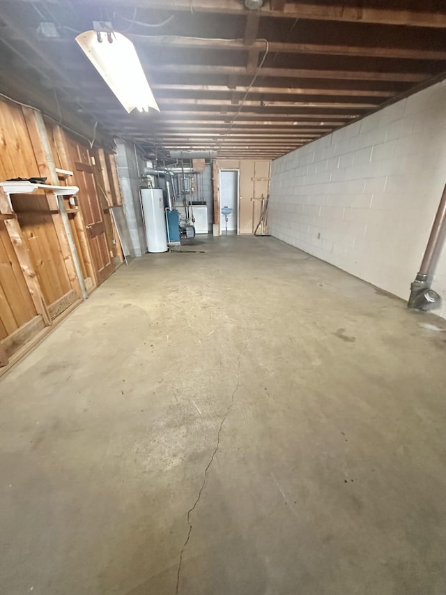 unfinished below grade area featuring concrete block wall and gas water heater