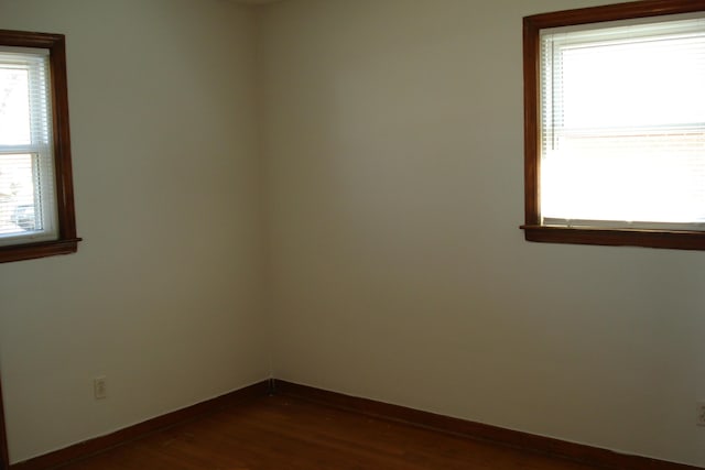 unfurnished room featuring baseboards and dark wood finished floors