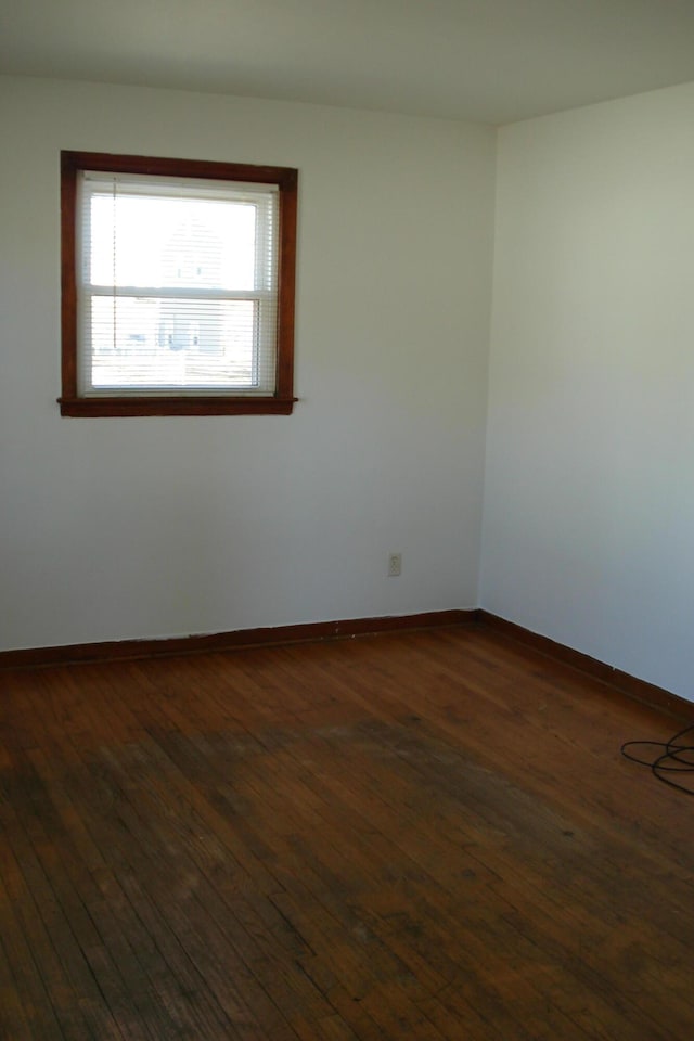 spare room featuring dark wood finished floors and baseboards