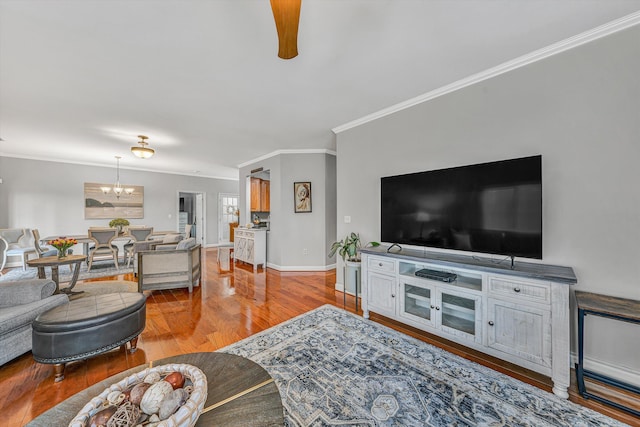 living room with a chandelier, baseboards, wood finished floors, and ornamental molding