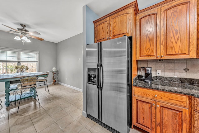 kitchen with ceiling fan, light tile patterned floors, decorative backsplash, stainless steel refrigerator with ice dispenser, and brown cabinetry