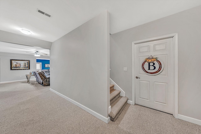 carpeted foyer featuring visible vents, baseboards, and ceiling fan