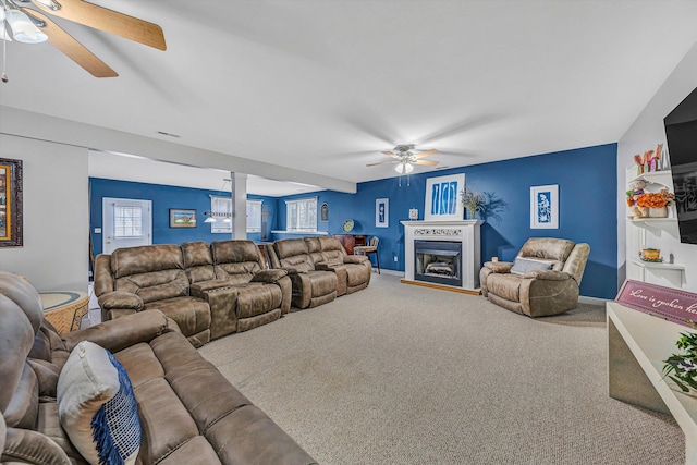 carpeted living area featuring a fireplace, decorative columns, a ceiling fan, and baseboards