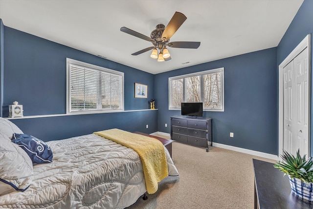 carpeted bedroom featuring a ceiling fan, multiple windows, baseboards, and a closet