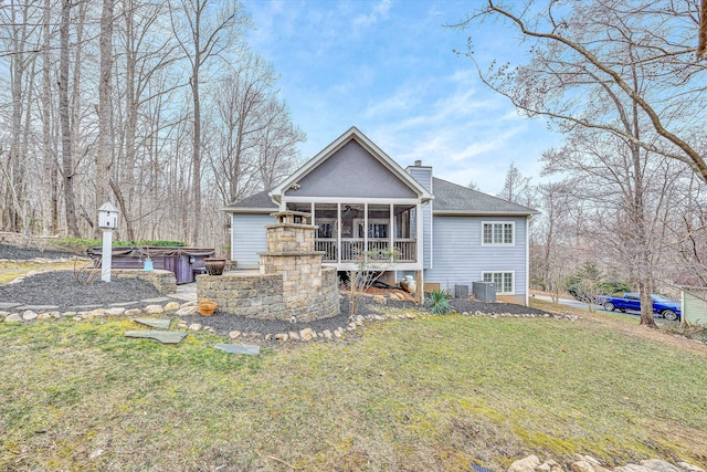 back of house featuring a shingled roof, cooling unit, a chimney, a yard, and a sunroom