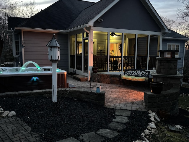 back of property with a patio, roof with shingles, a hot tub, and a sunroom