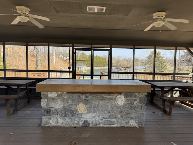 unfurnished sunroom with a ceiling fan and visible vents