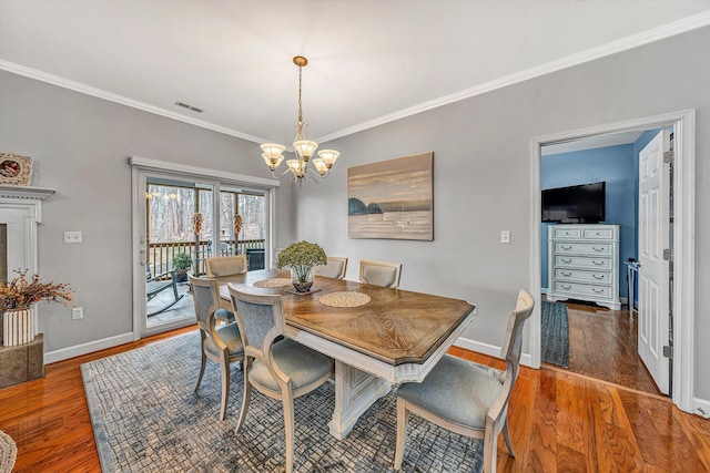 dining space with visible vents, baseboards, a chandelier, ornamental molding, and wood finished floors