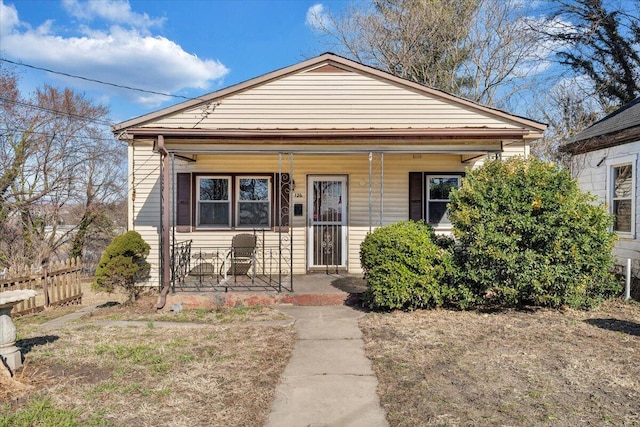 bungalow featuring covered porch and fence