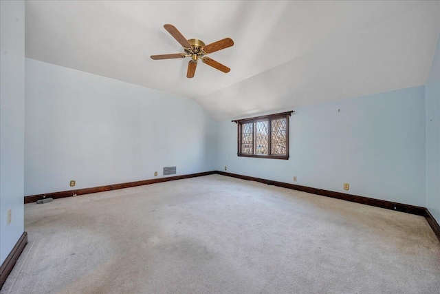 carpeted spare room with visible vents, baseboards, vaulted ceiling, and a ceiling fan