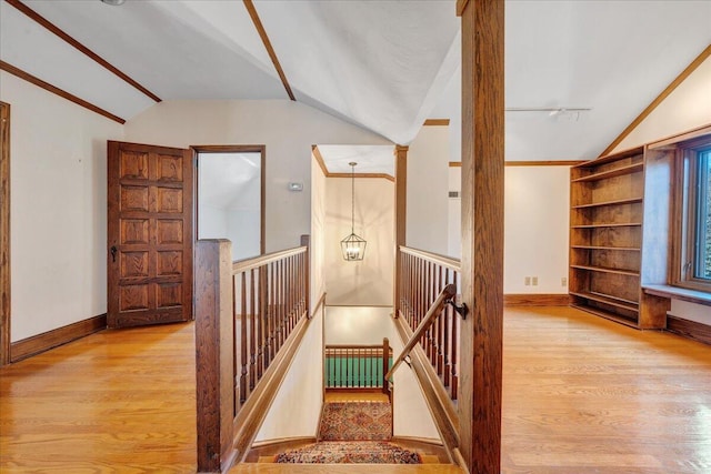 stairway with lofted ceiling, baseboards, and wood finished floors