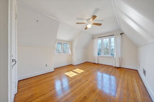 additional living space with lofted ceiling, ceiling fan, wood finished floors, visible vents, and baseboards