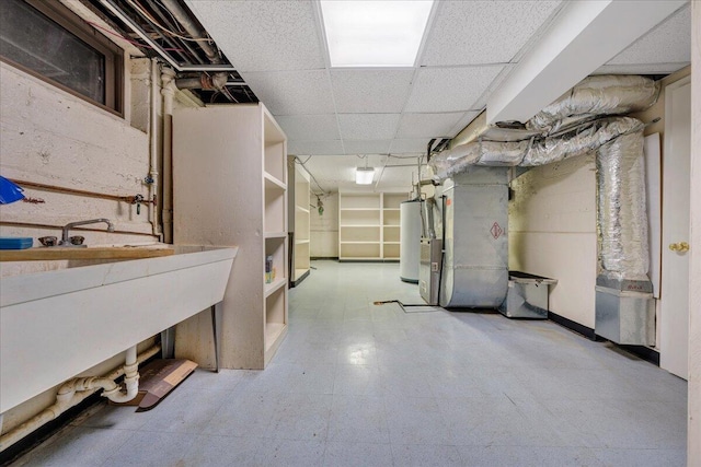 unfinished below grade area featuring a paneled ceiling, water heater, heating unit, and tile patterned floors