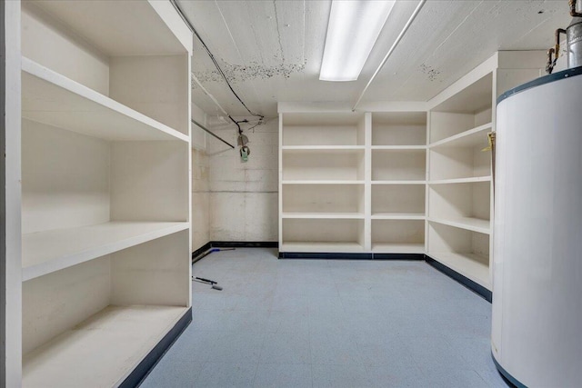 spacious closet with water heater and tile patterned floors