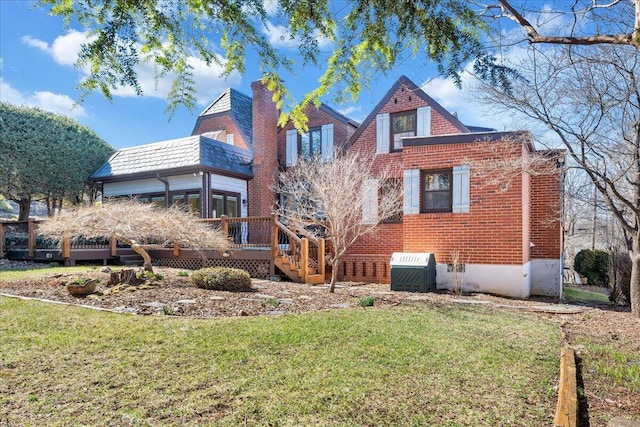 back of property with a wooden deck, a chimney, a yard, a high end roof, and brick siding