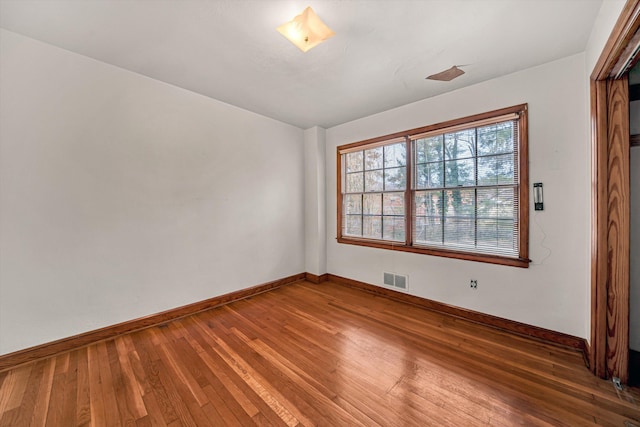 unfurnished room with visible vents, wood-type flooring, and baseboards