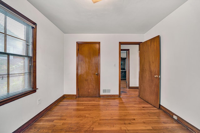 unfurnished bedroom with visible vents, baseboards, and wood finished floors