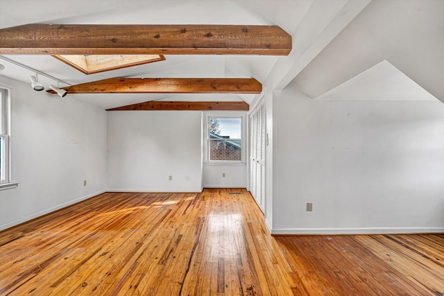 interior space with baseboards, vaulted ceiling with skylight, and wood-type flooring