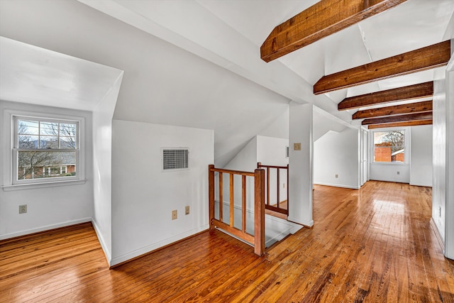 additional living space with visible vents, baseboards, hardwood / wood-style floors, and vaulted ceiling with beams