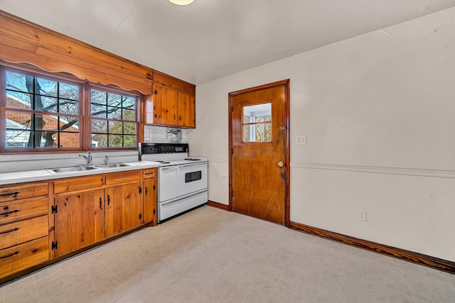 kitchen with white electric range, a sink, brown cabinetry, light countertops, and light floors