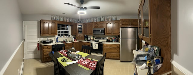 kitchen featuring light countertops, appliances with stainless steel finishes, glass insert cabinets, ceiling fan, and a sink