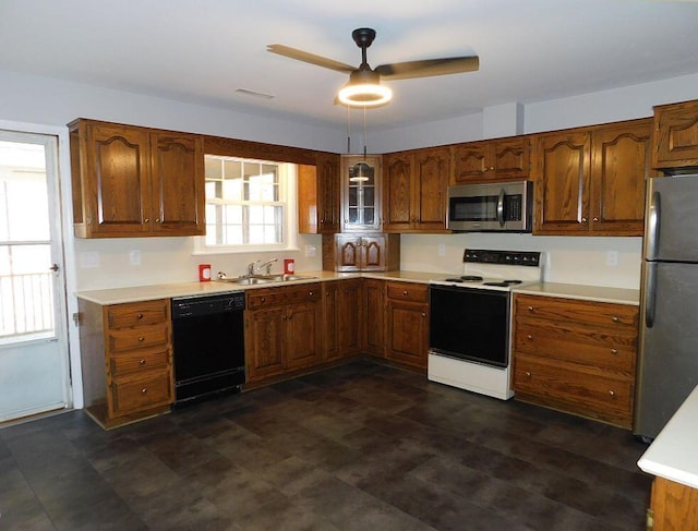 kitchen with brown cabinets, stainless steel appliances, light countertops, a sink, and ceiling fan