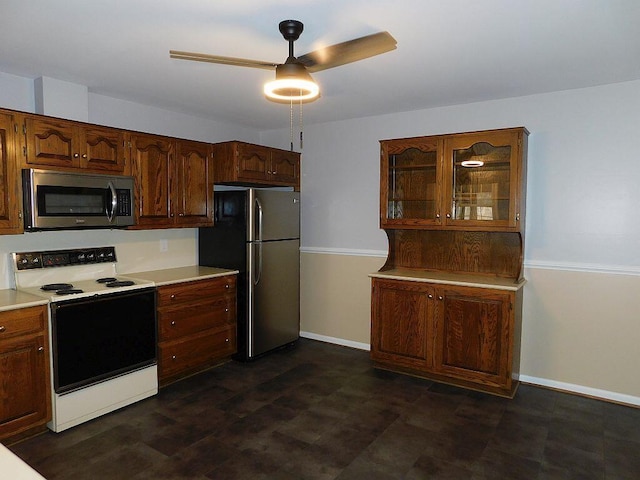 kitchen with stainless steel appliances, light countertops, glass insert cabinets, and a ceiling fan