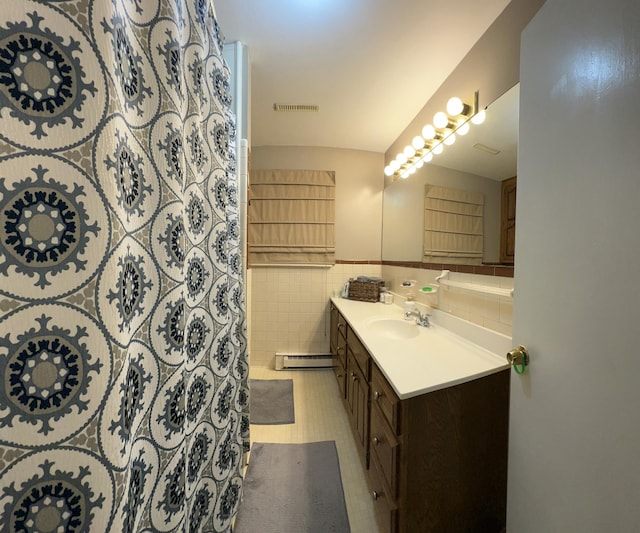 bathroom featuring tile walls, a baseboard radiator, visible vents, wainscoting, and vanity