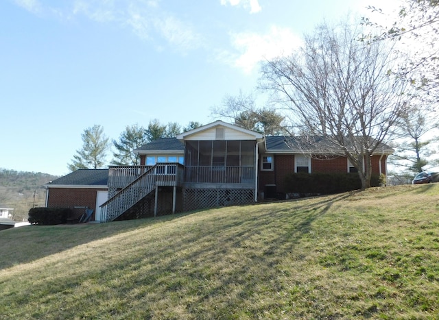 rear view of house with a sunroom, brick siding, a lawn, and stairs