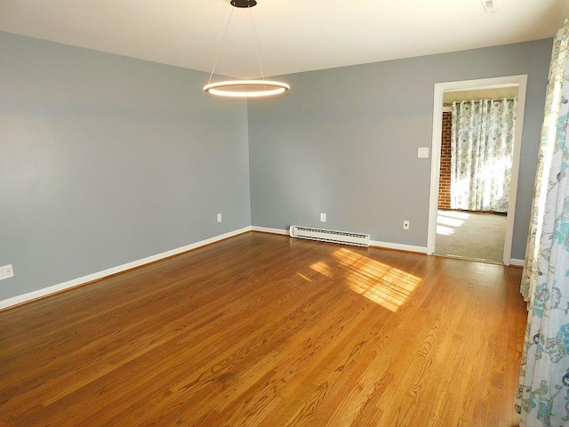 unfurnished room featuring a baseboard radiator, baseboards, and wood finished floors