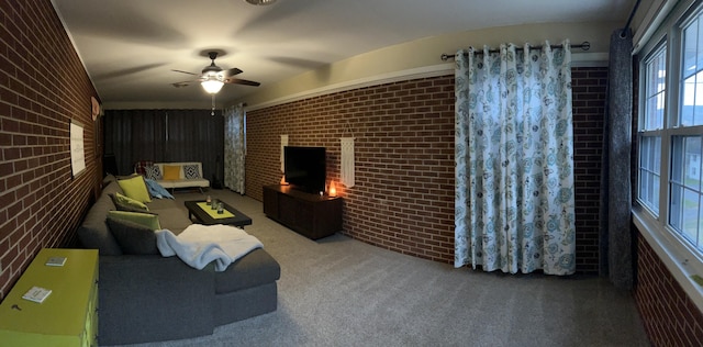 carpeted living room featuring a brick fireplace, brick wall, and a ceiling fan