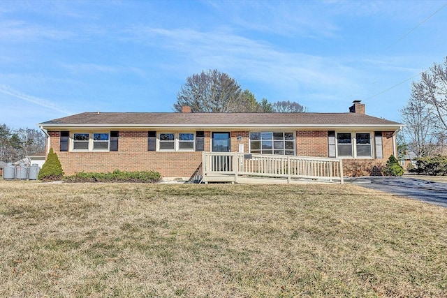 single story home with brick siding, a chimney, and a front yard