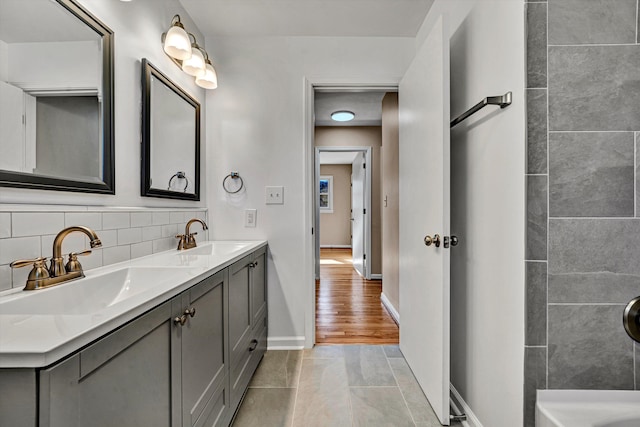 bathroom with tasteful backsplash, a sink, baseboards, and double vanity