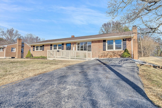 ranch-style house with a chimney, a front lawn, and brick siding