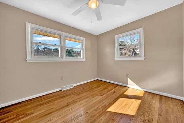 spare room with a healthy amount of sunlight, baseboards, and wood finished floors